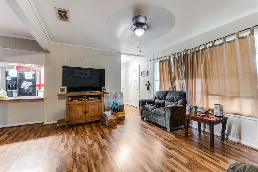 425 Lybrand Street Wills Point, TX 75169 - Photo 3 of 12 Living room featuring ornamental molding, wood finished floors, wood walls, and a ceiling fan