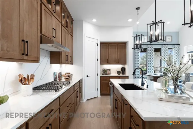 a kitchen with stainless steel appliances granite countertop a sink a stove and a wooden cabinets