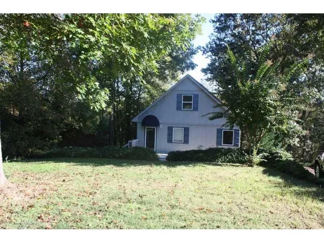 a view of house with yard and trees in the background