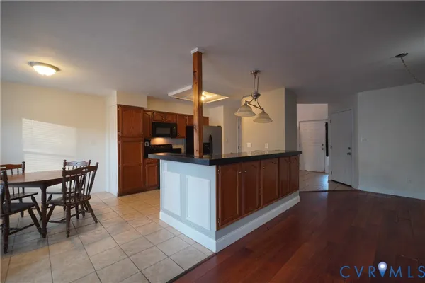 a kitchen with stainless steel appliances kitchen island granite countertop a table chairs and a refrigerator