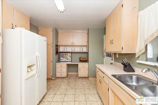 a kitchen with a refrigerator a sink and dishwasher with white cabinets