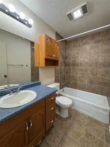 a bathroom with a granite countertop sink a toilet a mirror and shower