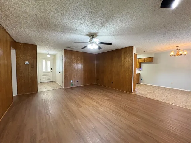 a view of an empty room with wooden floor and a ceiling fan