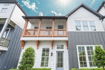614 Delmar Street Houston, TX 77023 - Photo 1 of 24 Modern house with a two-story design, featuring a charming balcony and large windows for natural light. The exterior combines white and dark gray paneling, accented by wooden elements and surrounded by neatly maintained greenery.