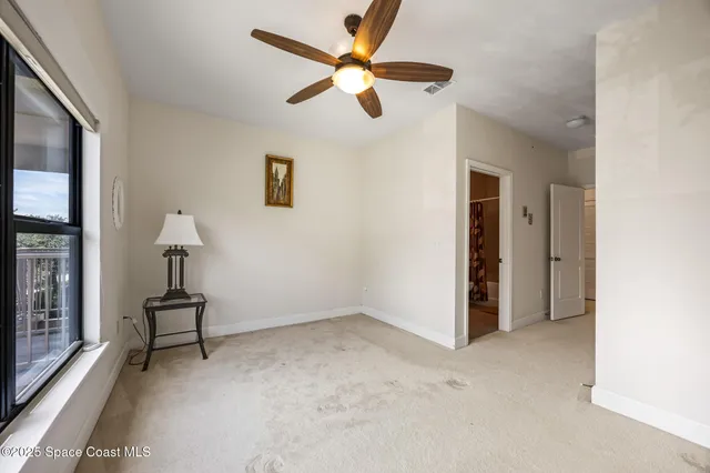 an empty room with chandelier fan and windows