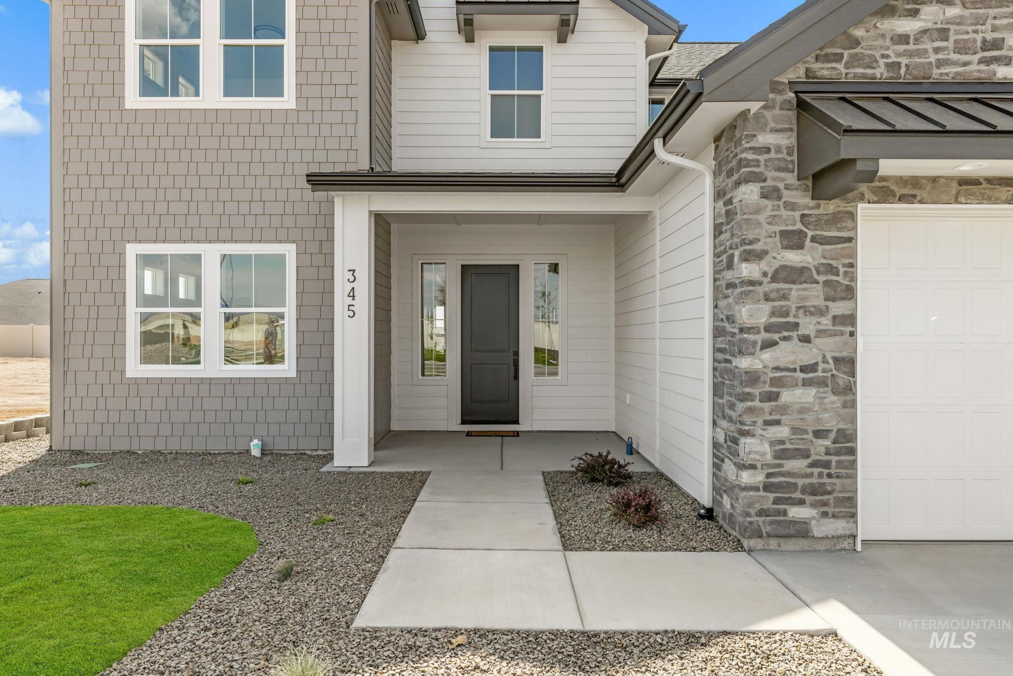 345 South Strut Way Boise, ID 83716 - Photo 3 of 50 Exterior featuring mixed siding, stone accents, a dark entry door with sidelight, and a concrete pathway