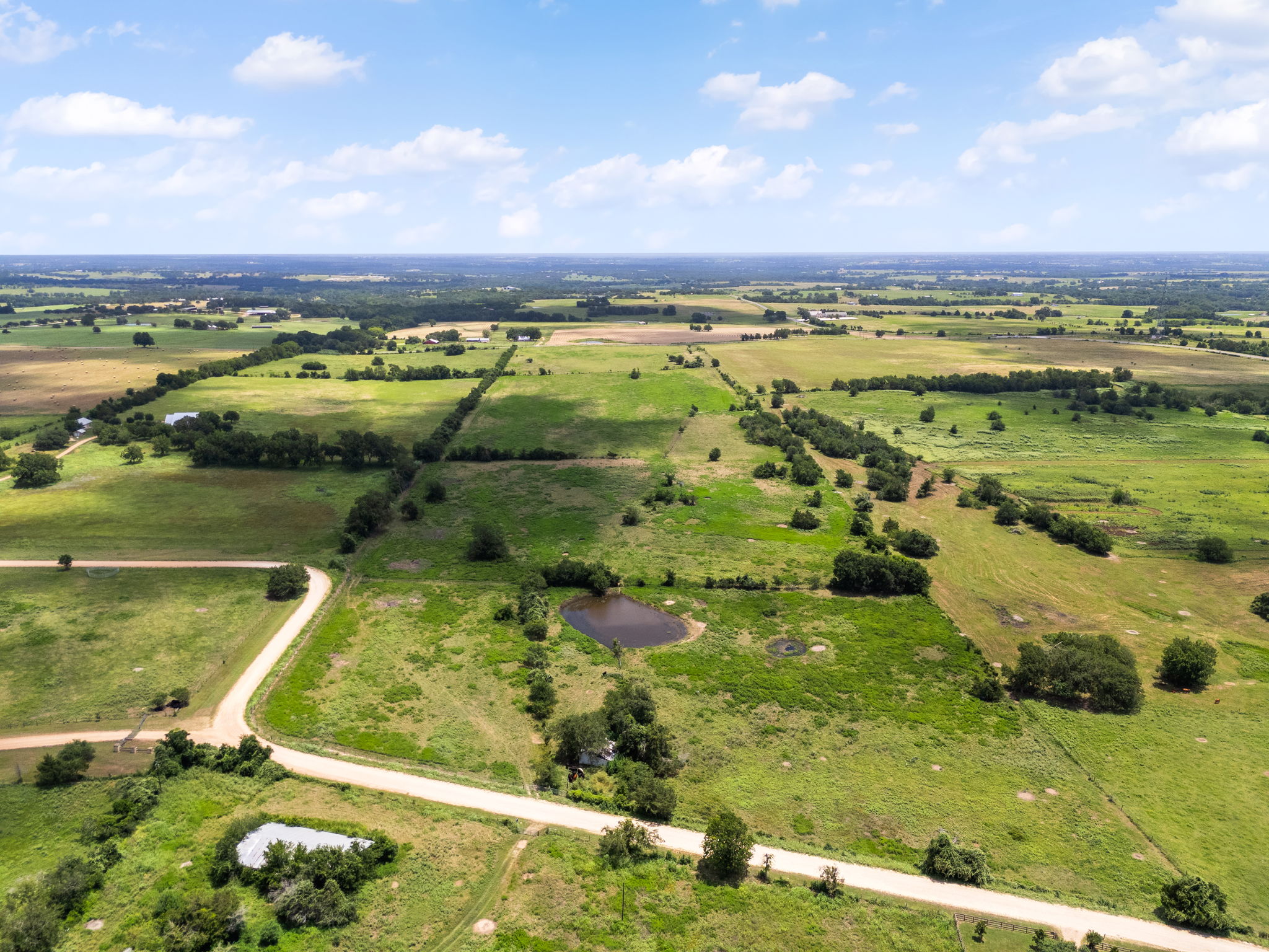 0 Thielemann Road Industry, TX 78944 - Photo 34 of 40 Vast green acreage unfolds under an open sky, offering secluded tranquility with a private pond and winding pathways.