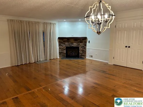 a view of a livingroom with wooden floor a chandelier and fireplace