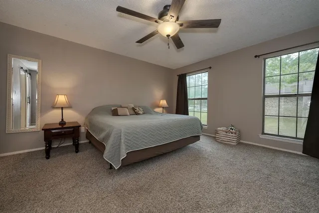 a bedroom with a bed painting on wall and two large window