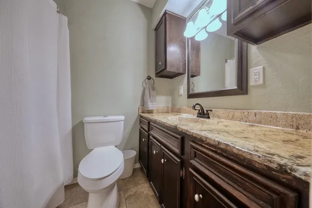 a bathroom with a granite countertop toilet sink and mirror
