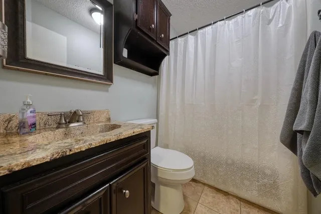 a bathroom with a granite countertop sink toilet and shower