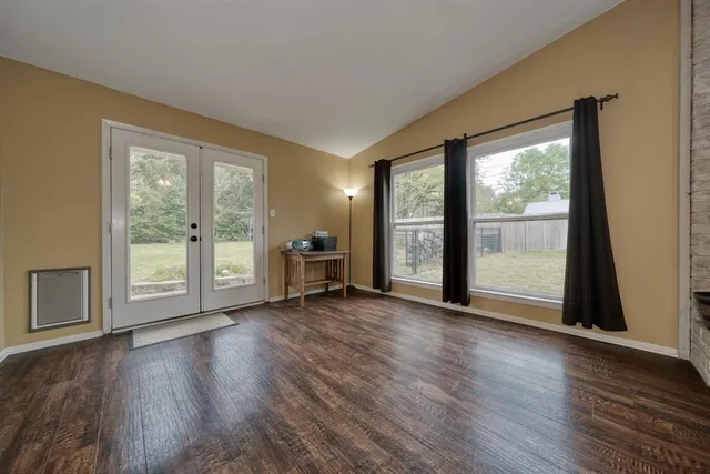 an empty room with wooden floor and windows