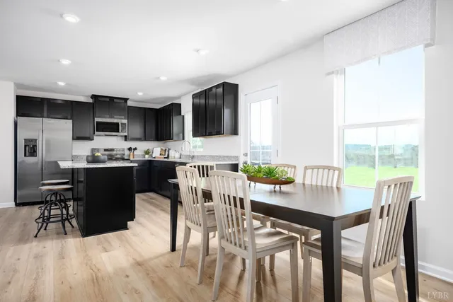 a kitchen with stainless steel appliances kitchen island granite countertop a table chairs and a refrigerator