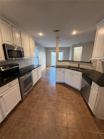 a kitchen with stainless steel appliances granite countertop a sink and stove top oven with wooden floor