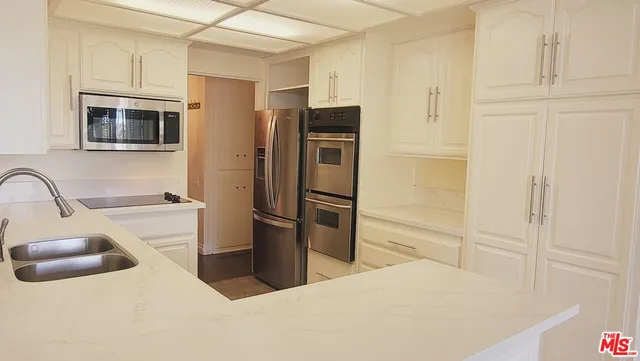 a kitchen with stainless steel appliances a refrigerator sink and microwave