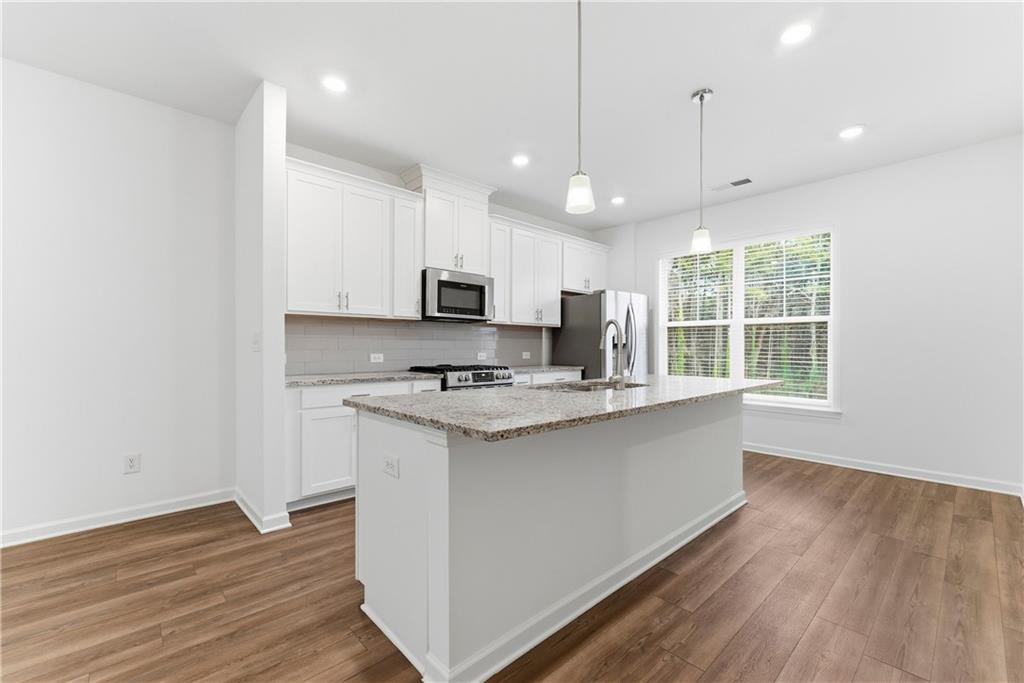 1621 Avery Way Tucker, GA 30084 - Photo 11 of 29 a kitchen with stainless steel appliances granite countertop a sink a stove a refrigerator and white cabinets with wooden floor