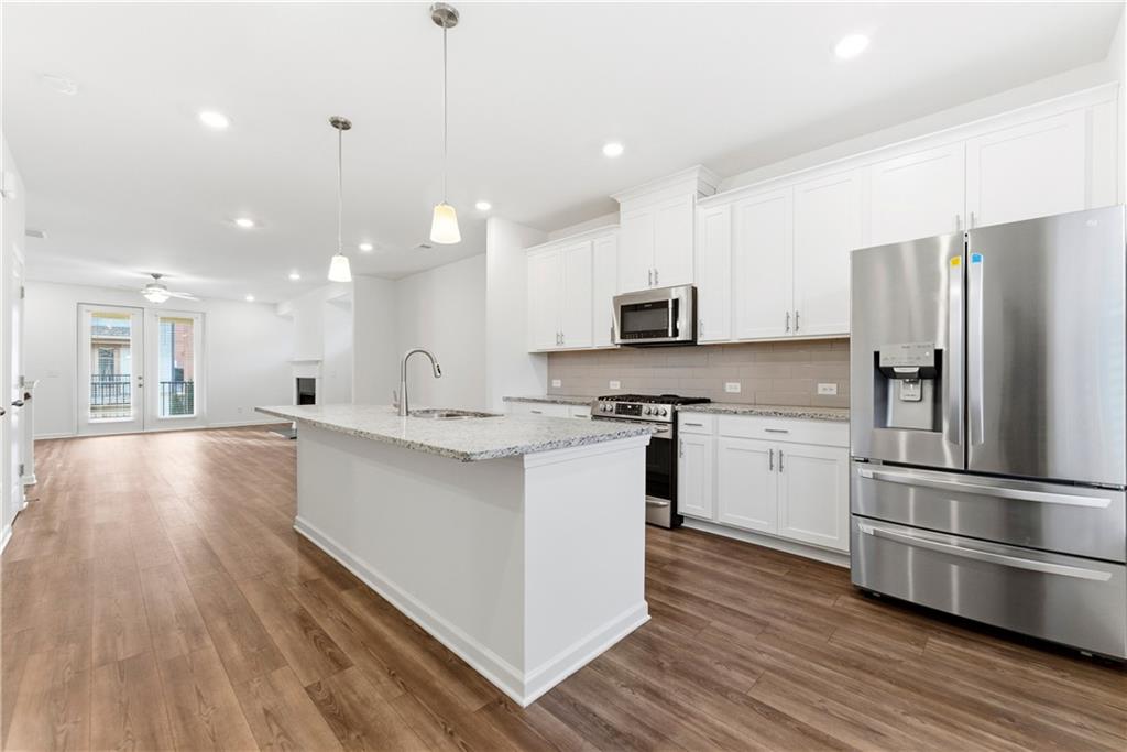 1621 Avery Way Tucker, GA 30084 - Photo 15 of 29 a large kitchen with kitchen island a sink dishwasher stove and white cabinets with wooden floor
