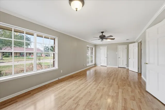a view of an empty room with a window and wooden floor