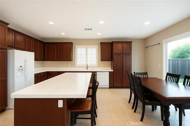 a kitchen with a table chairs refrigerator and window