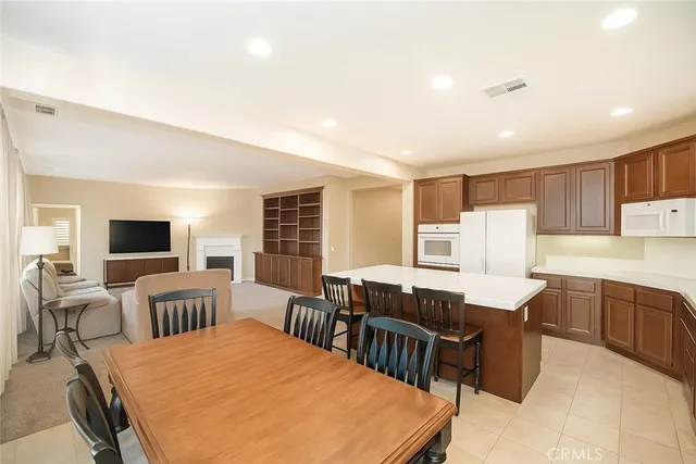 a large kitchen with kitchen island a dining table chairs and a refrigerator