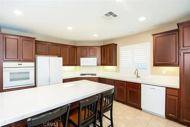 a kitchen with stainless steel appliances a sink a stove a refrigerator with wooden cabinets and island