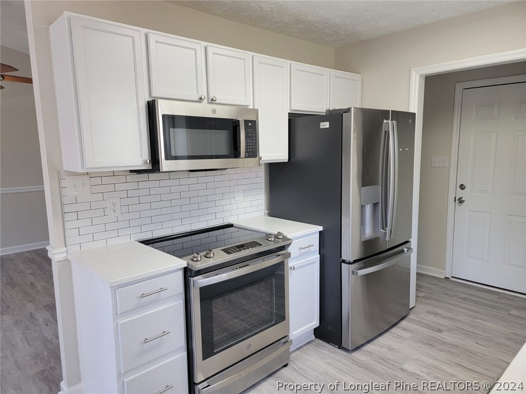 191 Rye Lane Raeford, NC 28376 - Photo 20 of 44 a kitchen with stainless steel appliances white cabinets and wooden floor