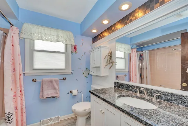 a bathroom with a granite countertop sink a mirror and a toilet