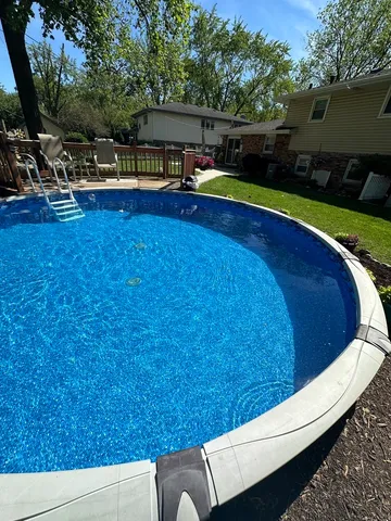 a view of swimming pool with seating area and trees in the background