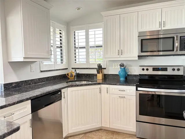 a kitchen with granite countertop white cabinets and appliances
