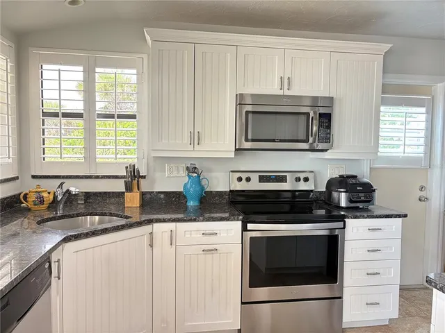 a kitchen with granite countertop white cabinets and stainless steel appliances