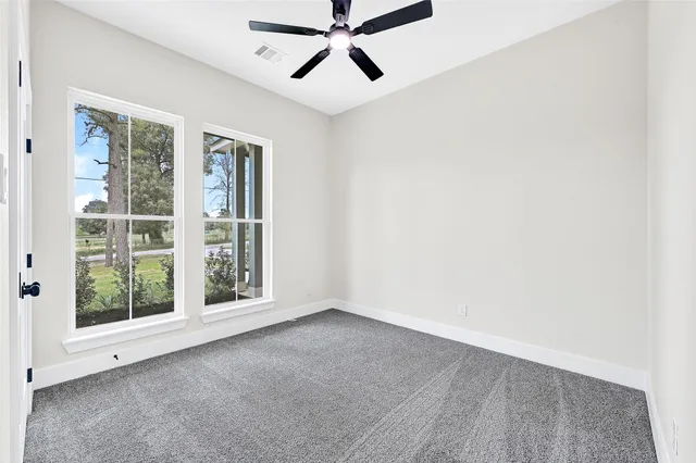 an empty room with windows and fan