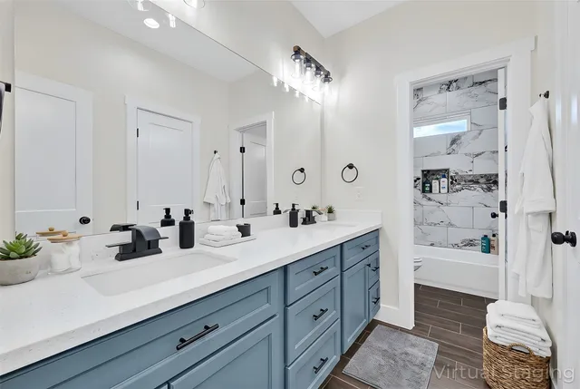 a bathroom with a double vanity sink a toilet a shower and a mirror