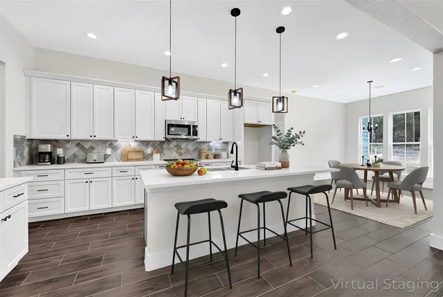 a kitchen with stainless steel appliances granite countertop a stove a sink a center island a dining table and chairs with wooden floor