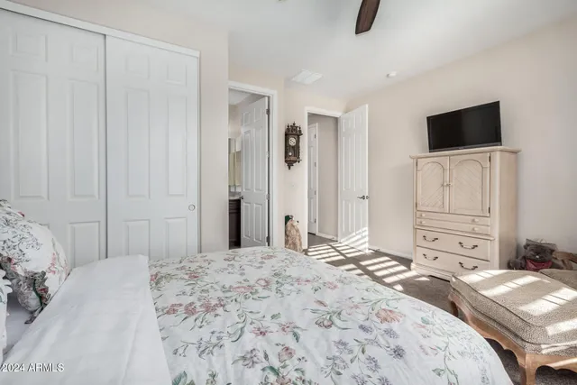 a bedroom with a bed and a flat tv screen on dresser
