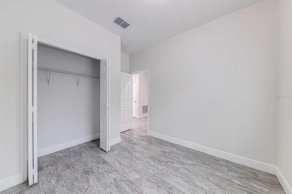 a view of an empty room with wooden floor and closet