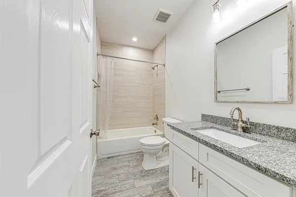a bathroom with a granite countertop sink a toilet and shower