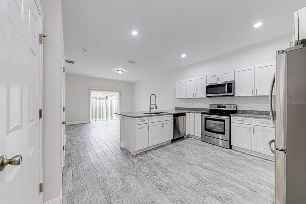 a kitchen with granite countertop a refrigerator and a stove top oven