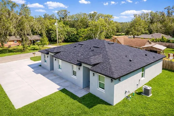 a view of house with backyard and bushes