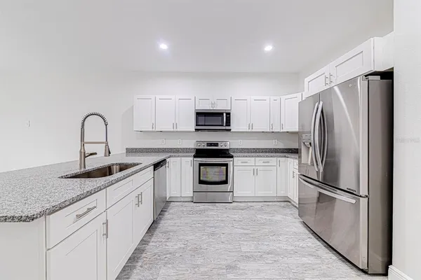 a kitchen with granite countertop a refrigerator stove and microwave