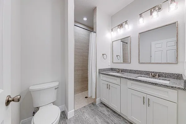 a bathroom with a granite countertop toilet sink and mirror