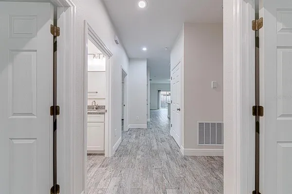 a view of a hallway with wooden floor and a bathroom