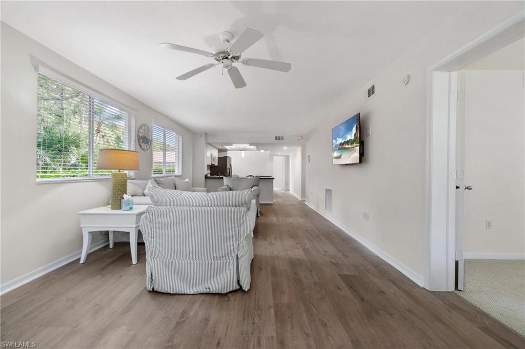 285 Naples Cove Drive, Unit 1106 Naples, FL 34110 - Photo 13 of 46 a living room with couches chairs and a large window with wooden floor