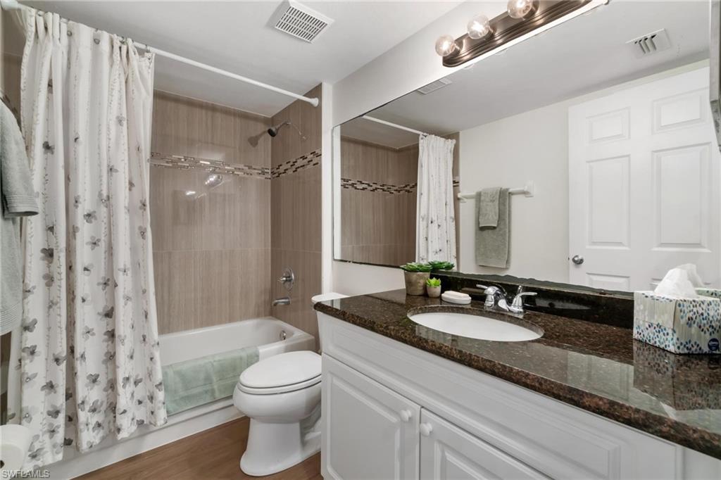 285 Naples Cove Drive, Unit 1106 Naples, FL 34110 - Photo 25 of 46 a bathroom with a granite countertop sink toilet a large mirror a shower and a bathtub