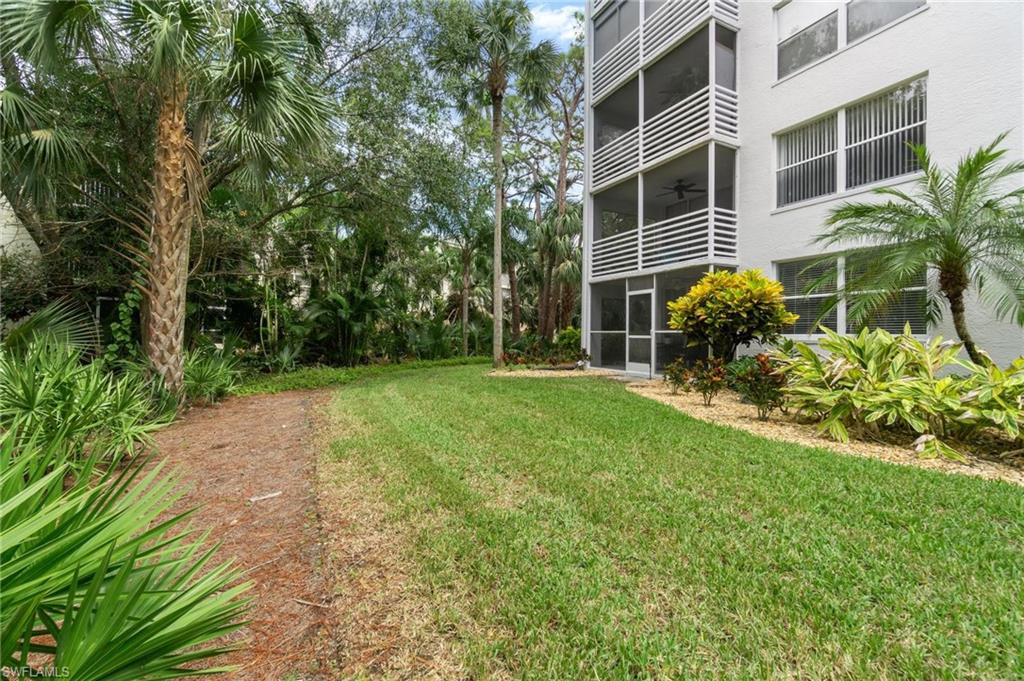 285 Naples Cove Drive, Unit 1106 Naples, FL 34110 - Photo 44 of 46 a view of a backyard with plants and large trees
