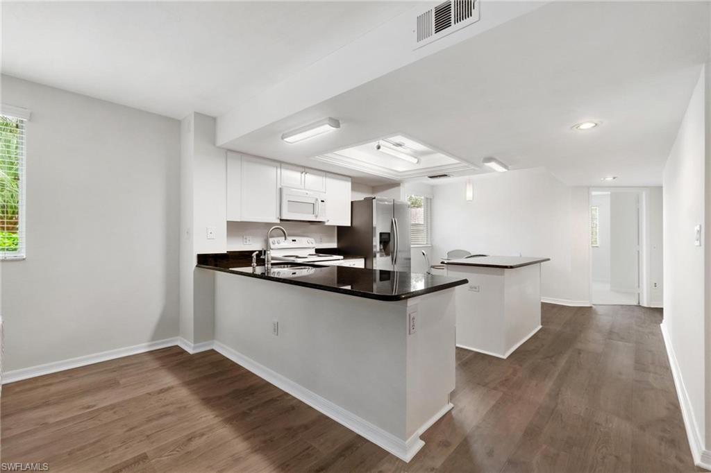 285 Naples Cove Drive, Unit 1106 Naples, FL 34110 - Photo 7 of 46 a kitchen with stainless steel appliances kitchen island sink refrigerator and microwave