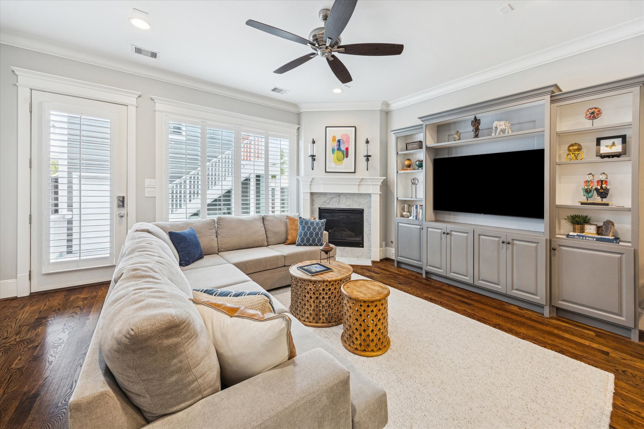 209 West 24th Street Houston, TX 77008 - Photo 7 of 36 The living room is highlighted by a wall of windows with plantation shutters overlooking the backyard, complemented by recessed lighting, crown molding, and a marble-surround fireplace.