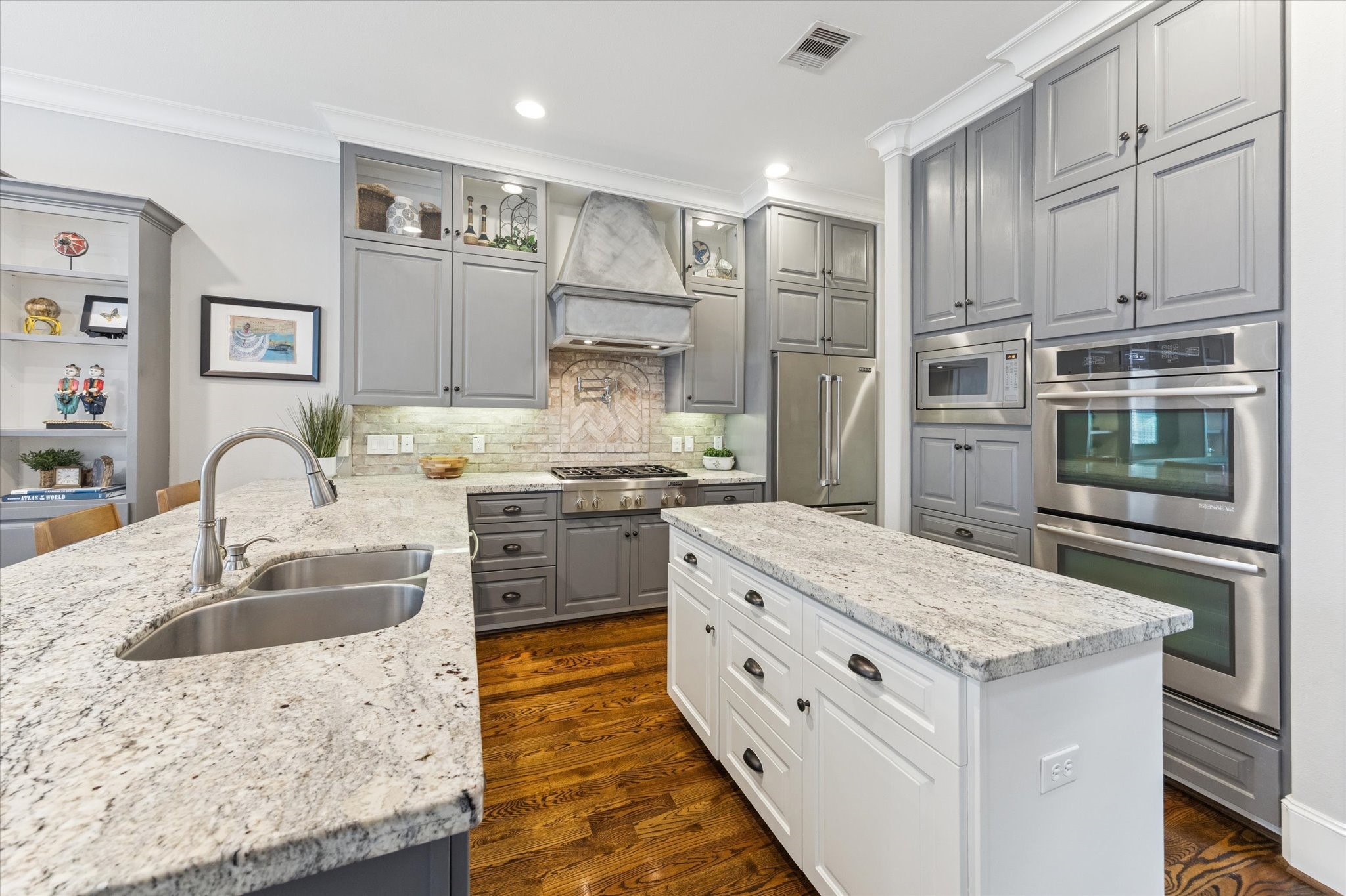 209 West 24th Street Houston, TX 77008 - Photo 9 of 36 A true chef’s kitchen with double ovens, a gas cooktop with range hood, abundant storage, and expansive counter space ideal for preparing meals.