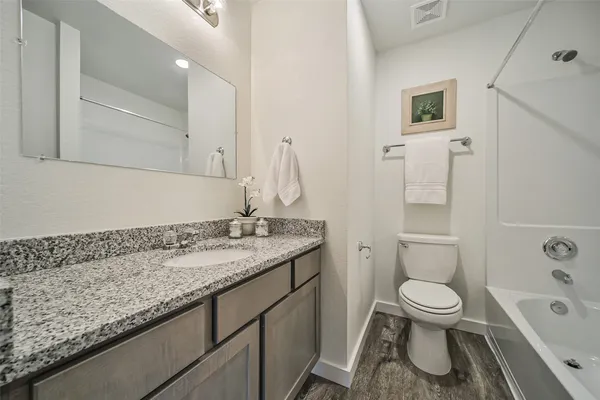 a bathroom with a granite countertop toilet a sink and a bathtub