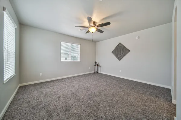 an empty room with windows and fan