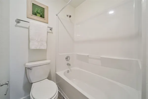 a white toilet sitting next to a bath tub